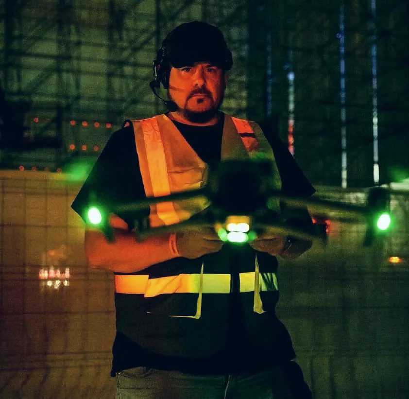 Piloto de drones de Linecam con el dron iluminado en un festival de noche