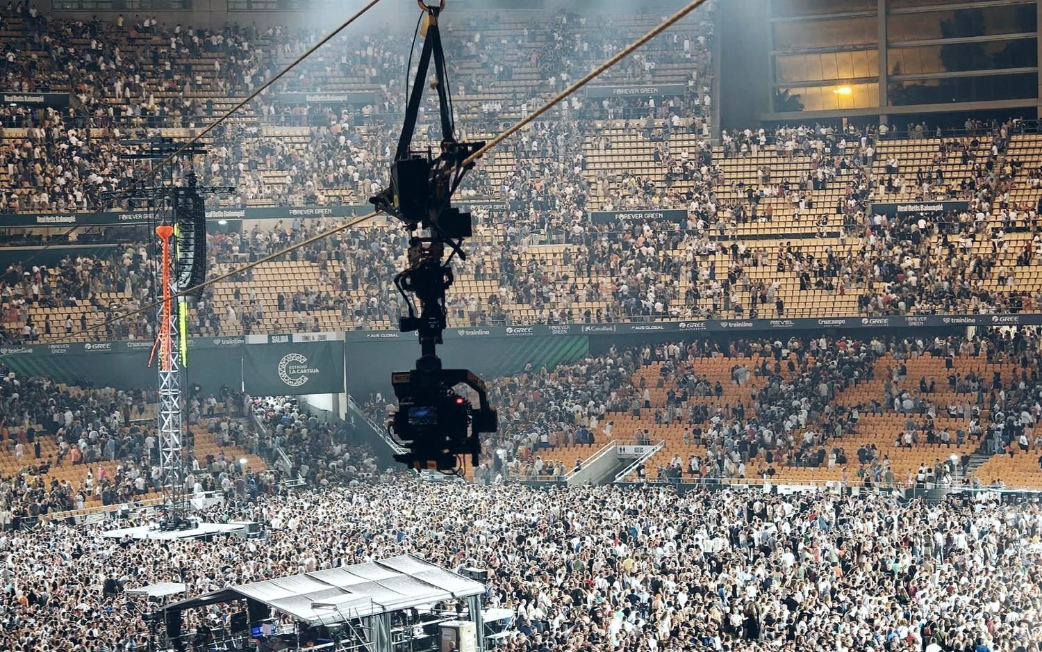 Linecam cablecam dolly travelling along the line above the crowd in a packed stadium at night