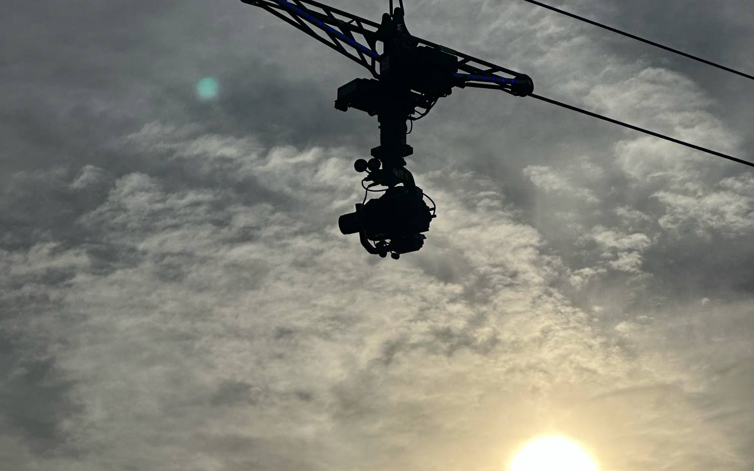 Linecam cablecam dolly hanging from the running line, silhouetted against the sky